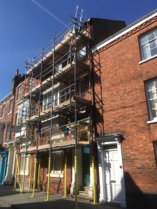 scaffolding equipment on front of terraced house going over pavement